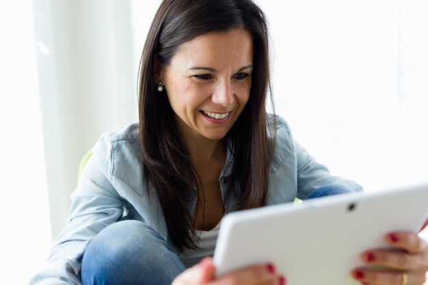 Belle jeune femme utilisant sa tablette numérique à la maison.