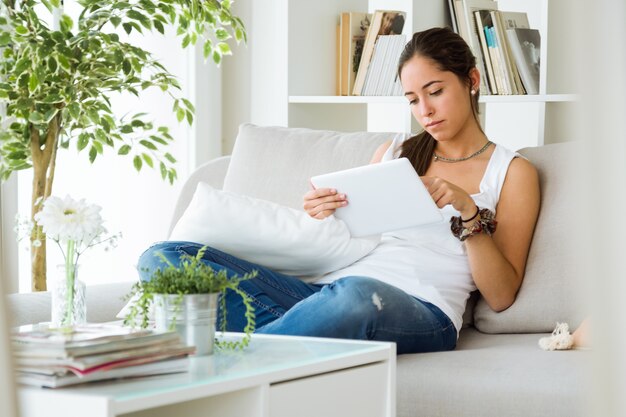 Belle jeune femme utilisant sa tablette numérique à la maison.