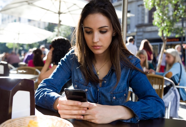 Belle jeune femme utilisant son téléphone mobile dans la rue.