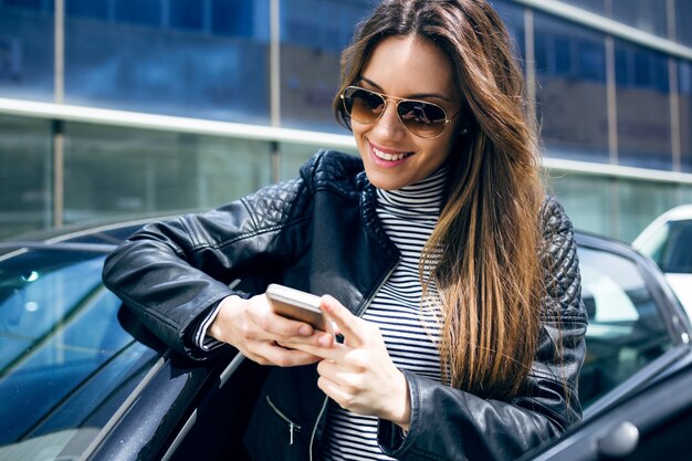 Belle jeune femme utilisant son téléphone mobile dans la voiture.