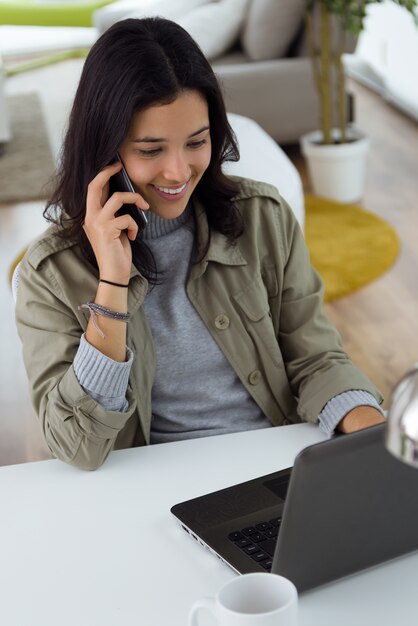 Belle jeune femme utilisant son téléphone mobile à la maison.