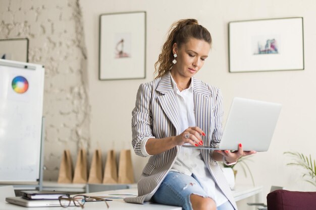 Belle jeune femme en veste rayée et jeans assis sur des