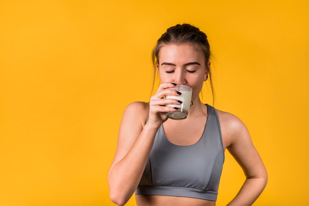 Belle jeune femme en vêtements de sport à boire du lait