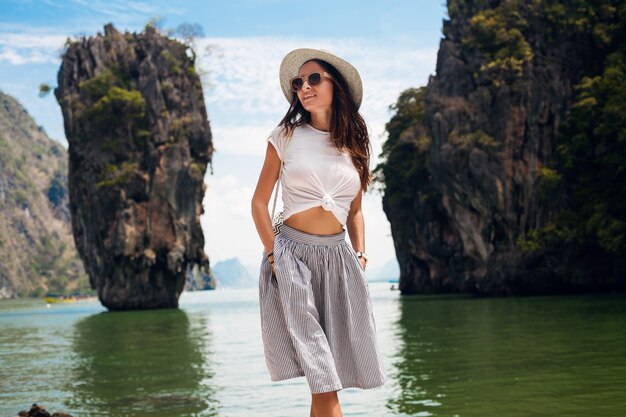 Belle jeune femme voyageant en Thaïlande, vacances d'été, style décontracté, lunettes de soleil, chapeau, jupe en coton, t-shirt, souriant, heureux, aventures