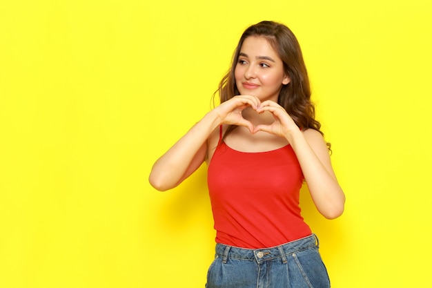 Une belle jeune femme vue de face en chemise rouge et jean bleu posant avec une expression ravie