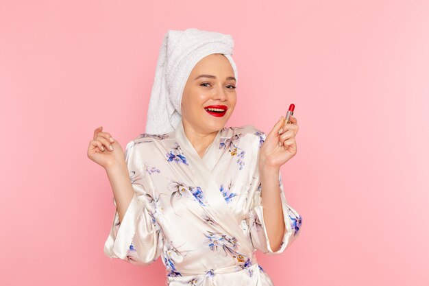 Une belle jeune femme vue de face en peignoir faisant du maquillage avec le sourire