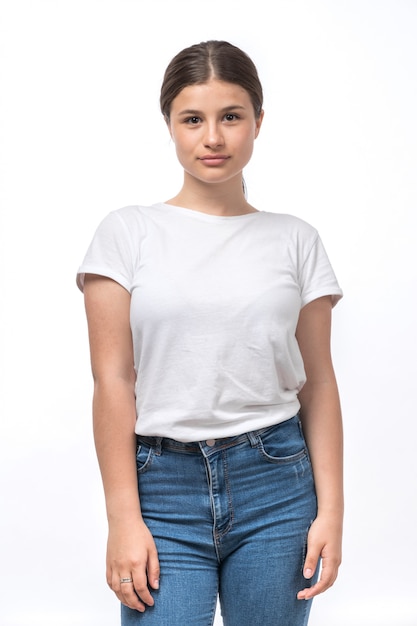 Une belle jeune femme vue de face en t-shirt blanc et jeans bleu posant