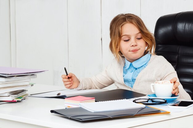 Belle jeune fille assise au lieu de travail au bureau.