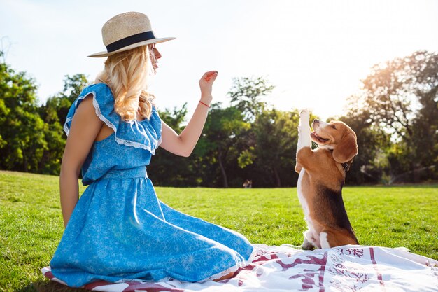 Belle jeune fille blonde marchant, jouant avec un chien beagle dans le parc.