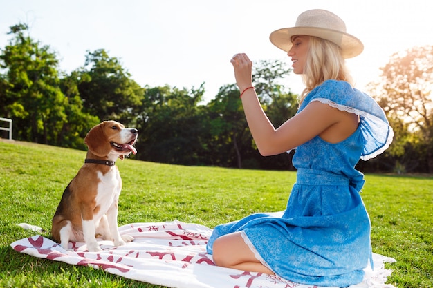 Belle jeune fille blonde marchant, jouant avec un chien beagle dans le parc.