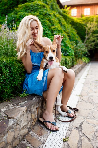 Belle jeune fille blonde marchant, jouant avec un chien beagle dans le parc.