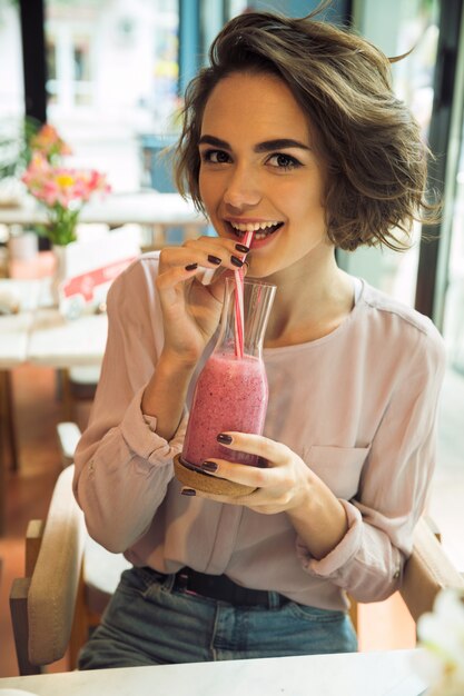 Belle jeune fille buvant un cocktail de smoothie