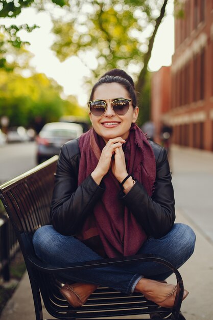 belle jeune fille dans une veste en cuir et une écharpe assis dans les rues de Chicago