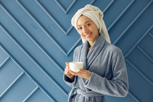 Belle jeune fille debout dans un studio dans un peignoir bleu