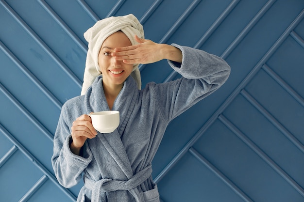 Belle jeune fille debout dans un studio dans un peignoir bleu