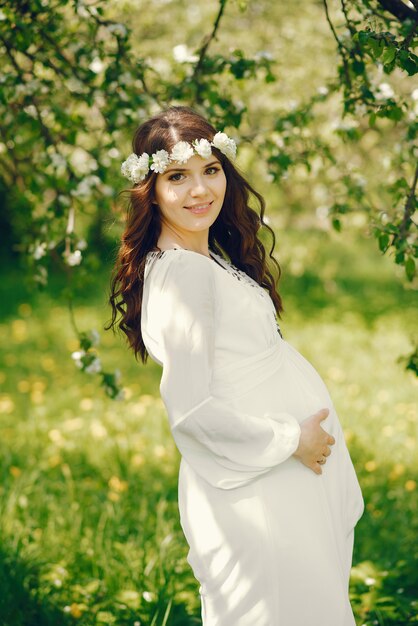 belle jeune fille enceinte dans une longue robe blanche et une couronne sur sa tête