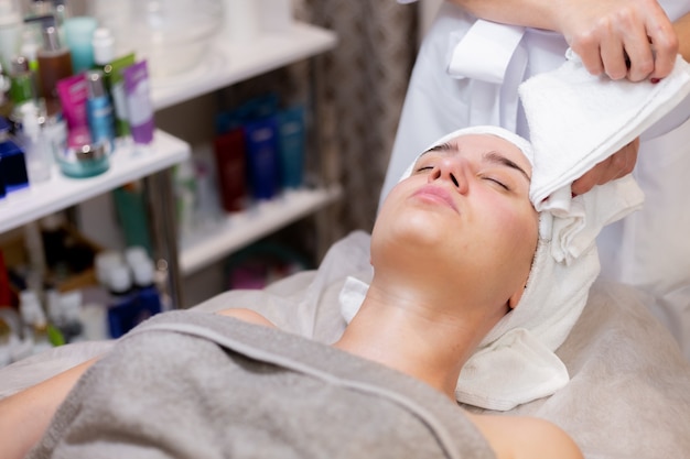 Une belle jeune fille est allongée sur la table de l'esthéticienne et reçoit des procédures, un léger massage du visage.