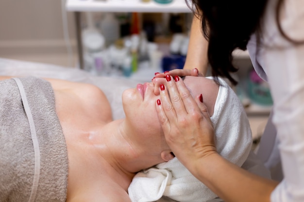 Une belle jeune fille est allongée sur la table de l'esthéticienne et reçoit des procédures, un léger massage du visage.