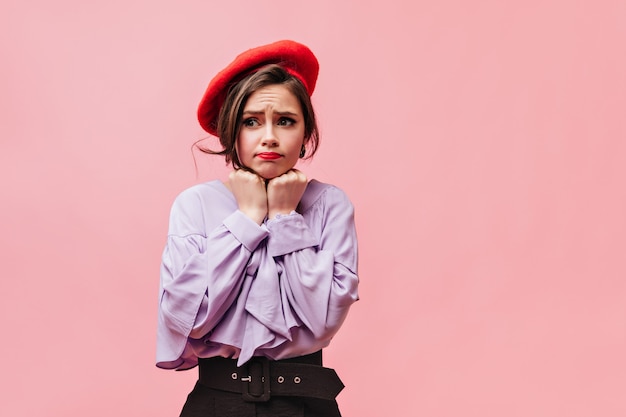 Photo gratuite belle jeune fille fait un visage innocent. portrait de dame en béret et chemisier élégant sur fond rose.