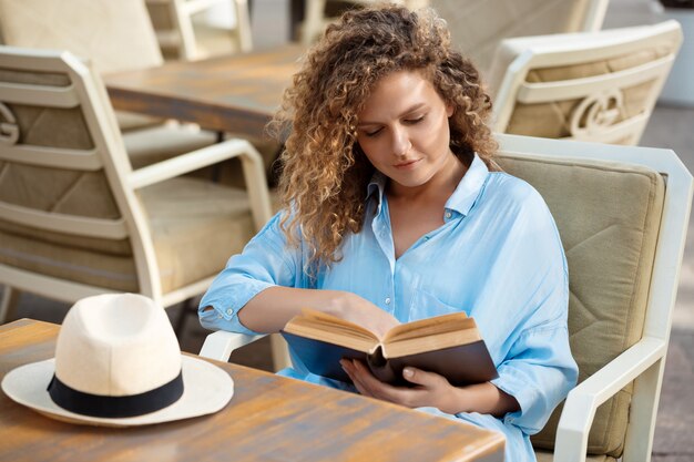 Belle jeune fille lisant, assis dans un café.