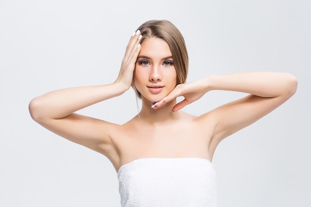 Belle jeune fille à la peau lisse sur un mur clair avec du maquillage naturel