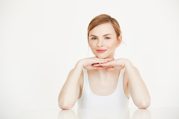 Belle jeune fille avec une peau propre parfaite souriant assis à table. Spa de beauté et cosmétologie.