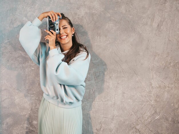 Belle jeune fille photographe souriante, prendre des photos à l'aide de son appareil photo rétro.