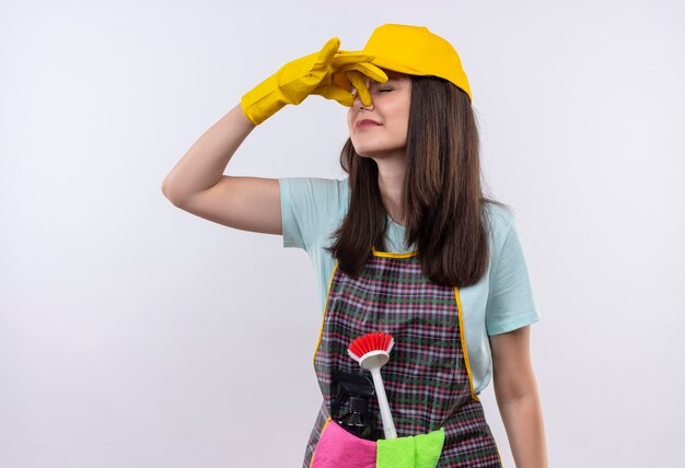 Belle jeune fille portant un tablier, une casquette et des gants en caoutchouc fermant noce avec les doigts souffrant de puanteur