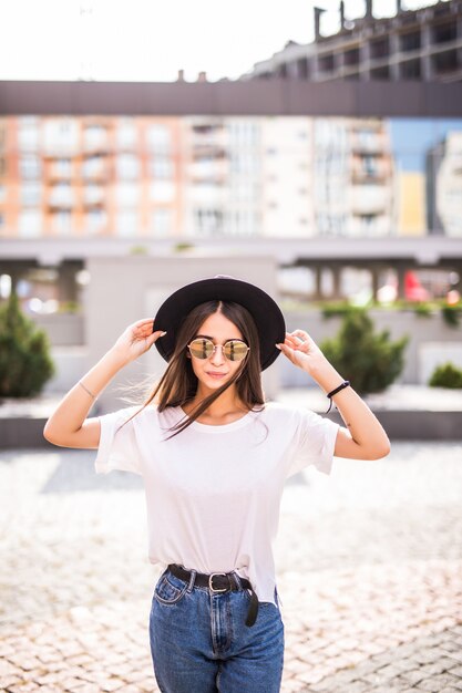 Belle jeune fille posant avec chapeau dans la rue