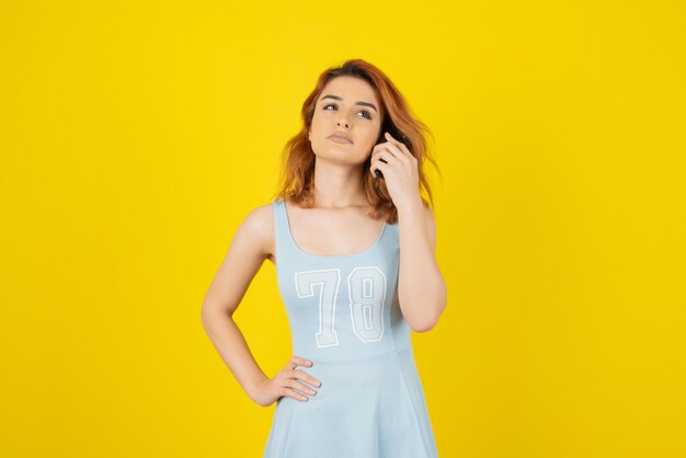 Belle jeune fille avec une robe bleue sur jaune.