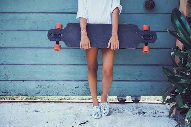 Photo gratuite belle jeune fille sexy en short avec longboard dans un temps ensoleillé