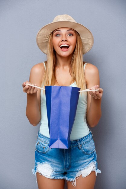 belle jeune fille tenant des sacs colorés sur fond gris.