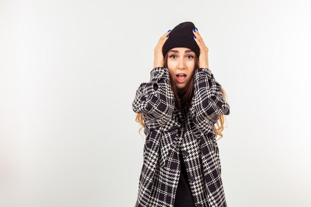 Belle jeune fille tenant ses mains sur sa tête et regardant la caméra avec la bouche ouverte