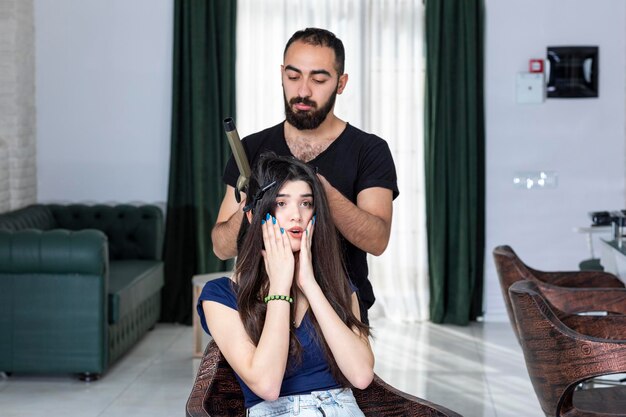 Belle jeune fille tient ses mains sur son visage pendant que Barber se coiffe Photo de haute qualité