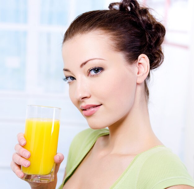 Belle jeune fille avec un verre de jus d'orange frais