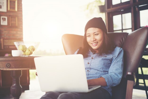 Belle jeune hippie femme assise avec son ordinateur portable et le café