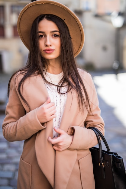 Belle jeune jolie femme marchant le long de la rue vêtu de vêtements décontractés automne manteau lumineux