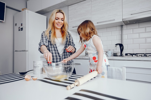 Une belle jeune maman avec sa petite fille cuisine dans la cuisine à la maison