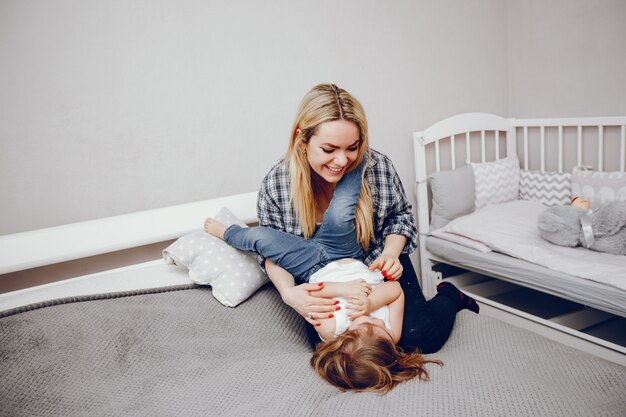 Une belle jeune maman avec sa petite fille jouant à la maison