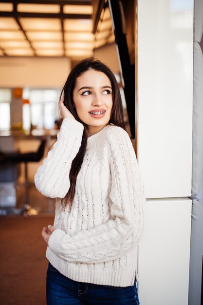 Belle jeune mannequin aux grands yeux lèvres rouges et longs cheveux bruns reste dans la chambre chez elle