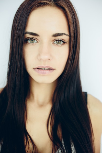 Belle jeune mannequin posant contre un mur blanc