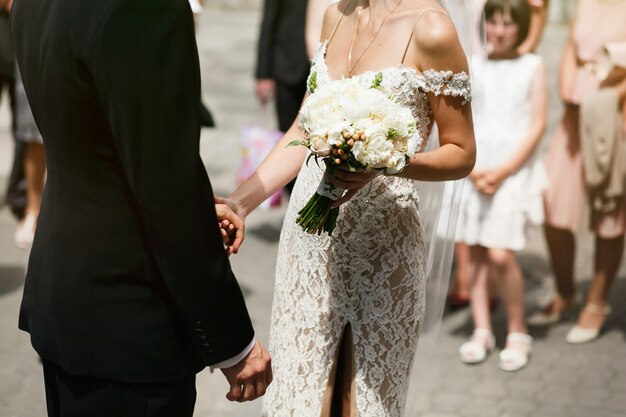Belle jeune mariée sexuelle en robe vintage vintage et beau marié se tiennent les mains