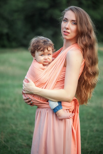 Belle Jeune Mère étreignant Son Petit Fils De Tout-petit Contre L'herbe Verte.