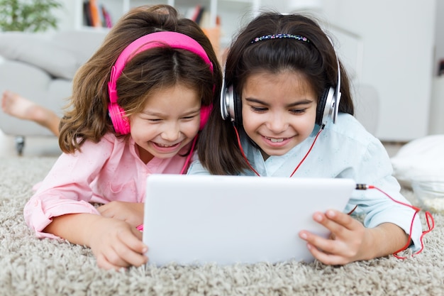 Belle jeune soeur écoutant de la musique avec une tablette numérique