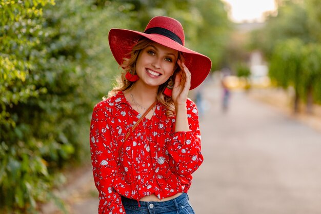Belle jolie femme souriante blonde élégante en chapeau rouge de paille et tenue de mode d'été chemisier
