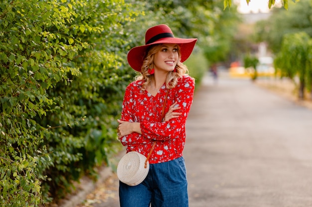 Belle jolie femme souriante blonde élégante en chapeau rouge de paille et tenue de mode d'été chemisier