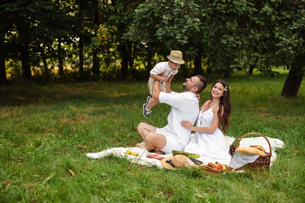 Belle maman, papa et leur mignon petit enfant s'amusent ensemble et sourient dehors