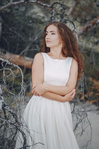 Belle mariée aux cheveux longs dans une magnifique robe blanche dans la nature