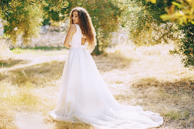 Belle mariée aux cheveux longs dans une magnifique robe blanche marchant dans la nature