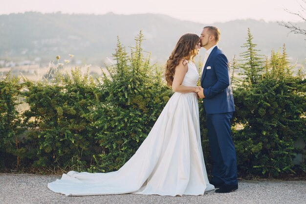 belle mariée aux cheveux longs en robe blanche avec son jeune homme marchant dans la nature